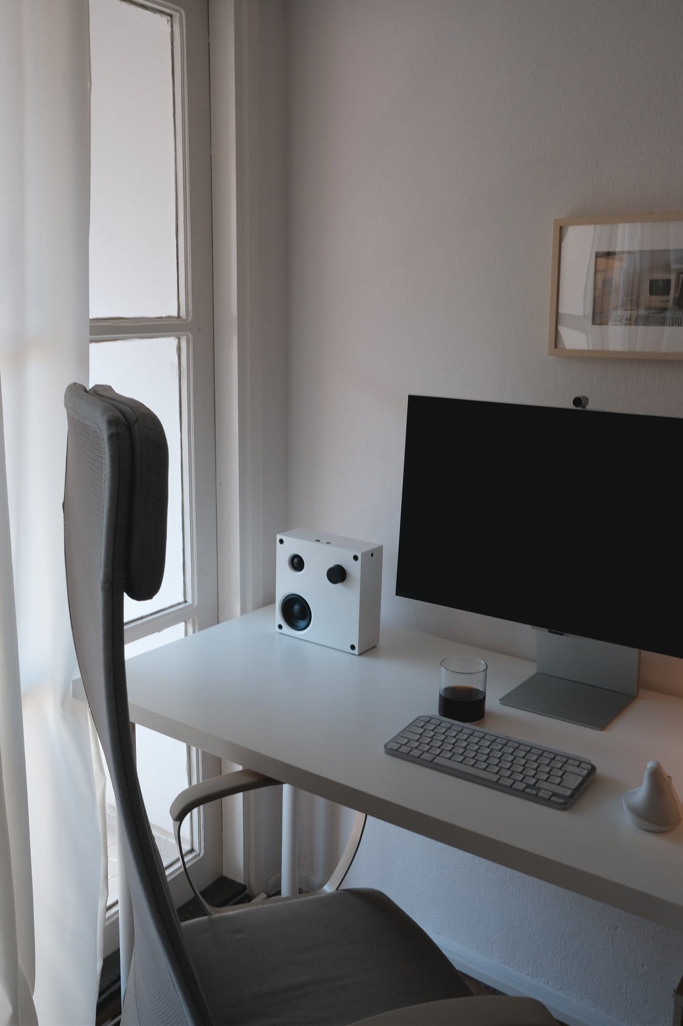 A minimalist home office with a Samsung Viewfinity S9 monitor, Logitech MX Keys Mini Mac keyboard, IKEA VAPPEBY speakers, and an IKEA MARKUS chair