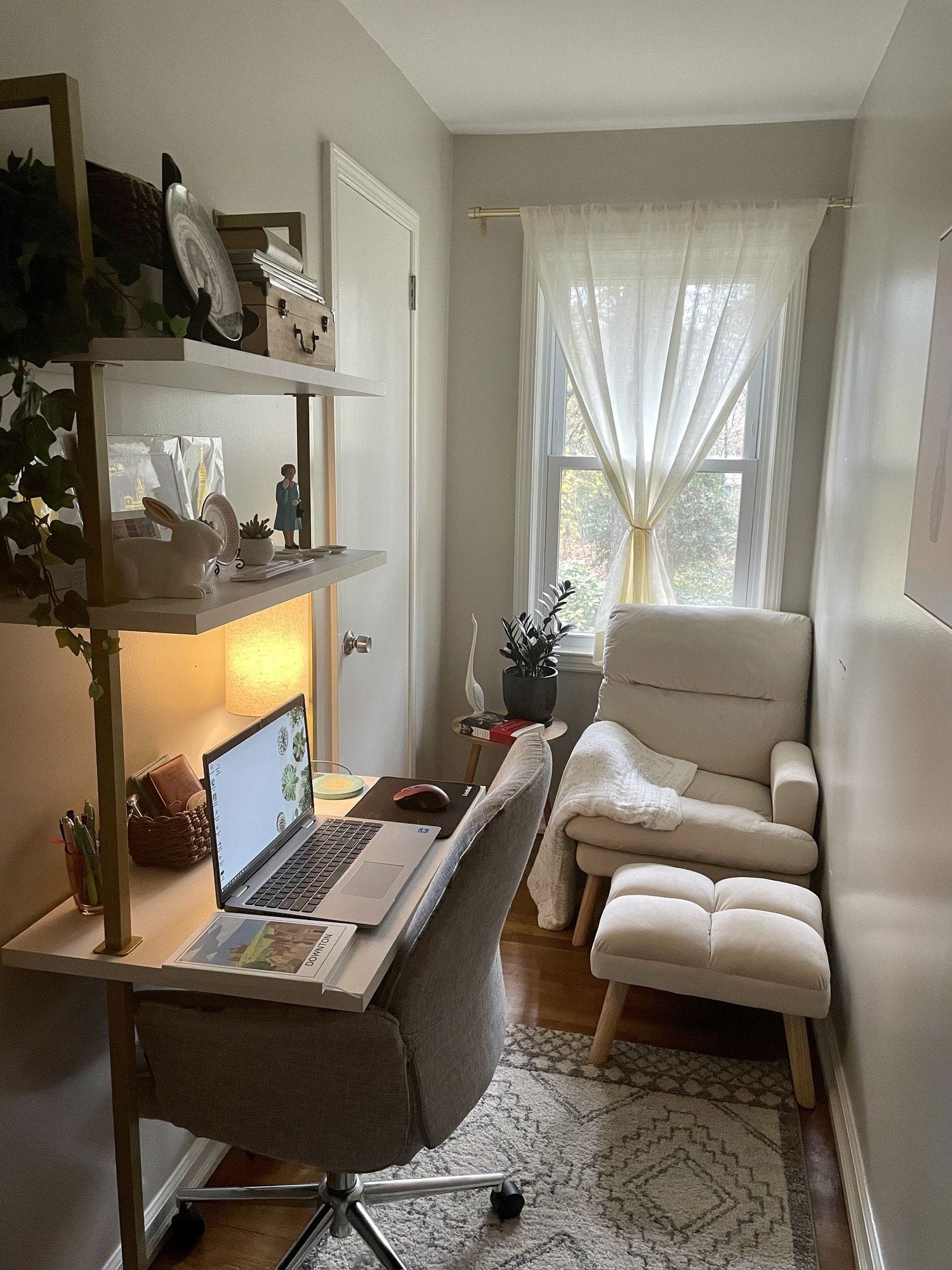 A tall, vertically built home office nook with a laptop desk and cream reading chair by the window